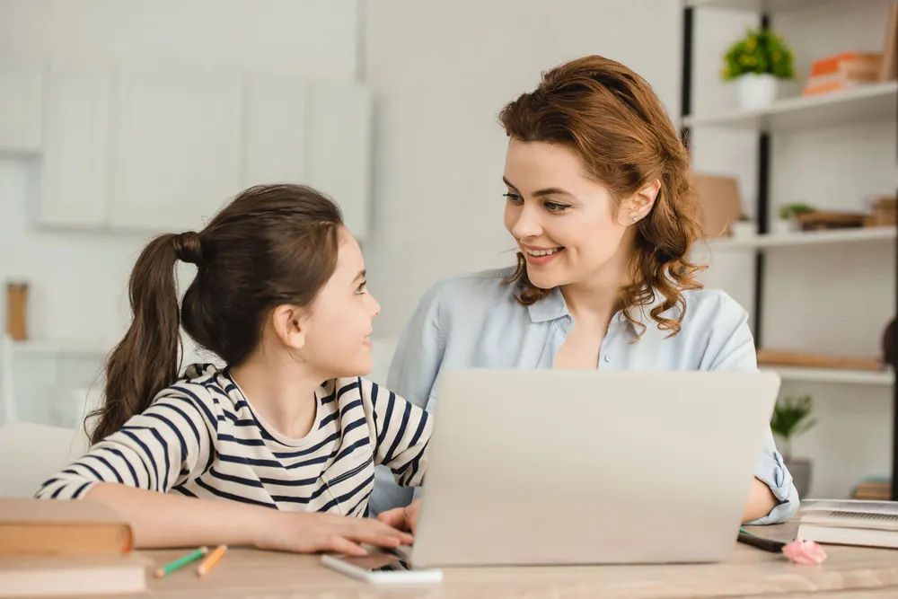 A mother and daughter working through a lesson together on a laptop