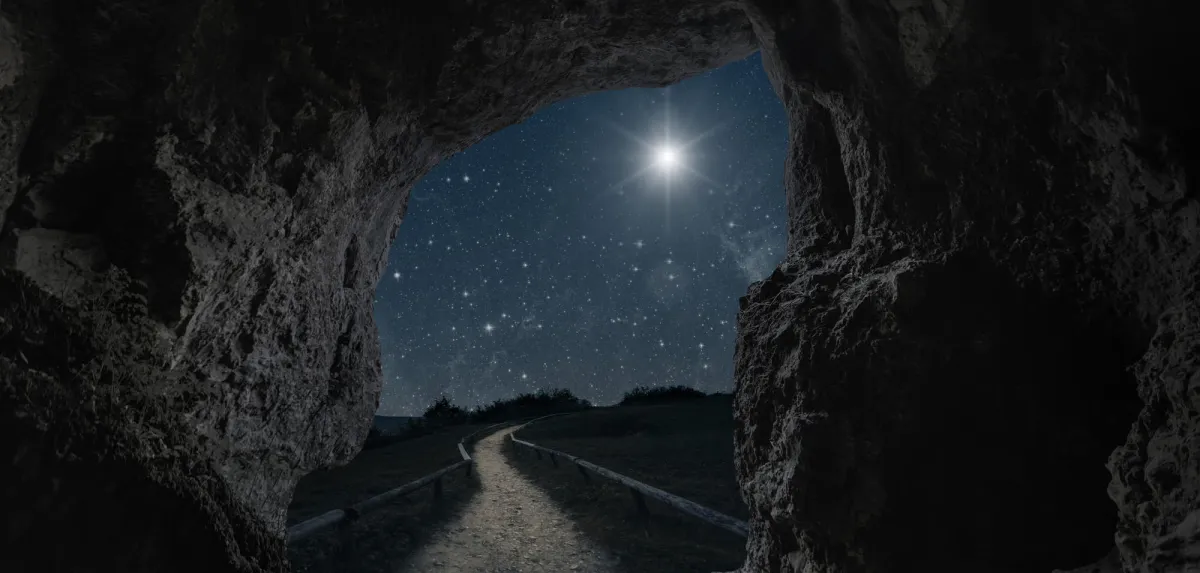 A bright star shining over a moonlit path that winds away from the mouth of a cave